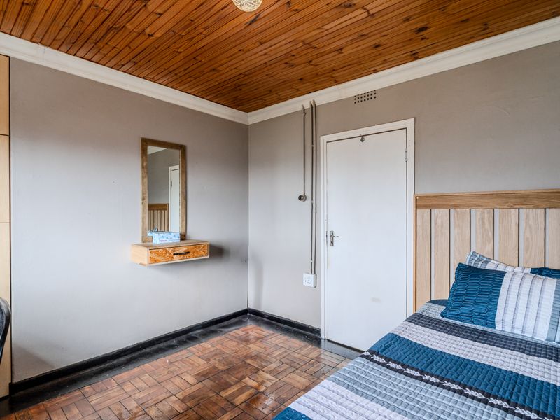 Bedroom featuring parquet flooring, a timber-paneled ceiling, built-in wardrobe, and a wall-mounted vanity unit.