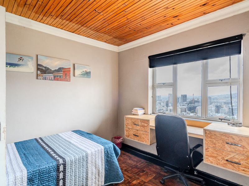 Bedroom featuring parquet flooring, a timber ceiling, and a built-in desk positioned under a window with city views.