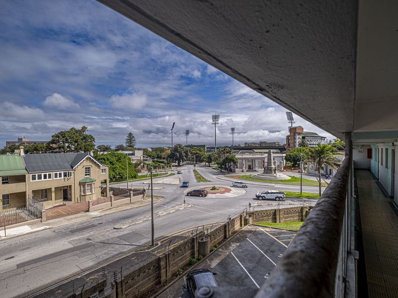 Elevated view overlooking a suburban street intersection and local landmark from an apartment balcony with a weathered concrete structure.