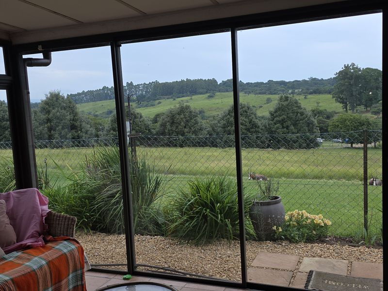 Enclosed patio area featuring large sliding glass doors that provide expansive views of the surrounding green landscape and garden.