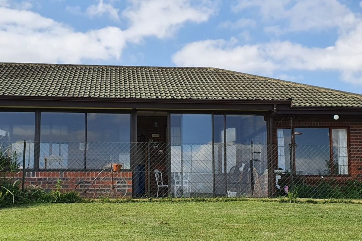 Rear elevation of a townhouse featuring a tiled roof, brick exterior, and extensive sliding glass doors opening onto a garden area.