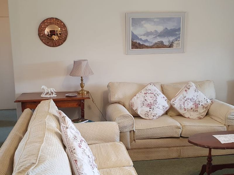 A comfortable living room featuring carpeted flooring and neutral wall finishes, providing a traditional and inviting space for relaxation.