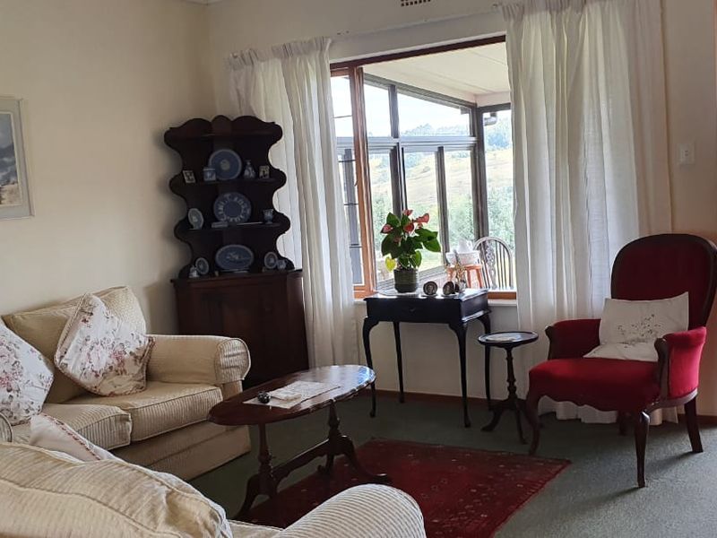 A comfortable living room featuring large windows that provide natural light and direct access to an outdoor patio area with scenic views.