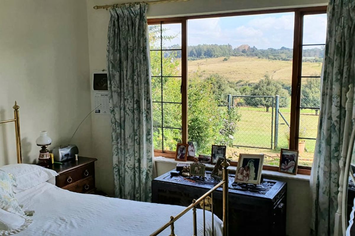 A cozy bedroom featuring a large window that provides natural light and scenic views of the surrounding landscape.