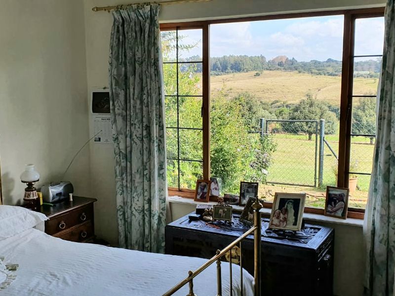 A cozy bedroom featuring a large window that provides natural light and scenic views of the surrounding landscape.