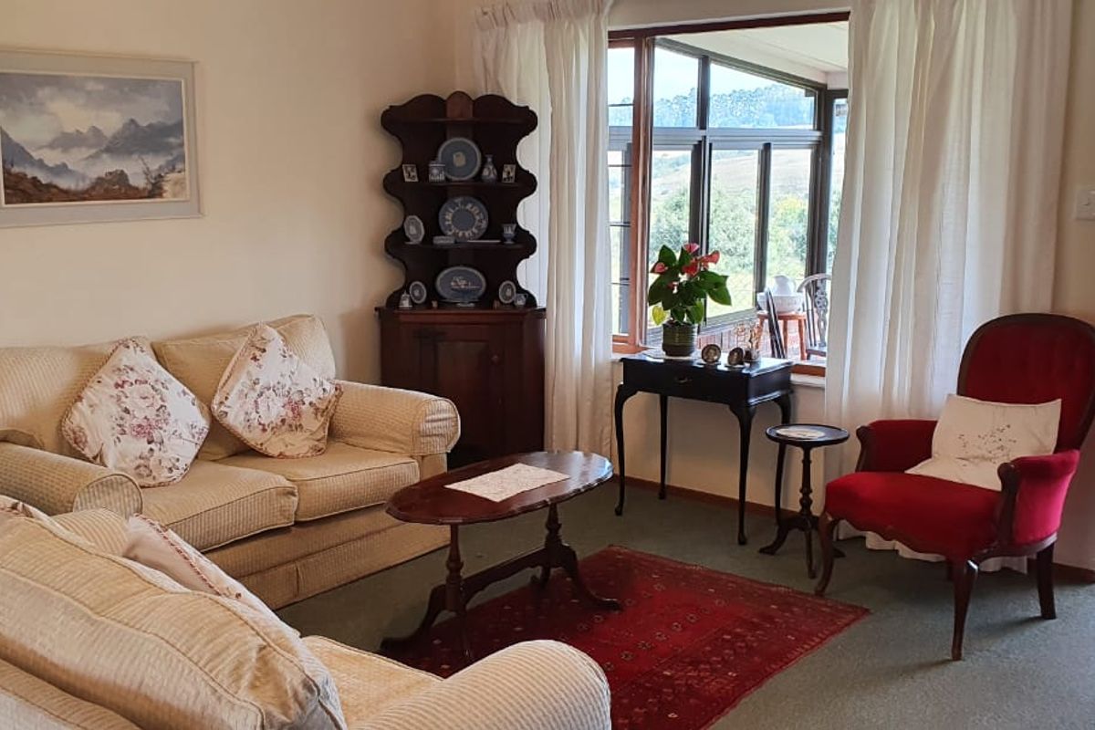 A comfortable living room featuring large windows and a sliding door that provides access to an outdoor patio area with scenic views.