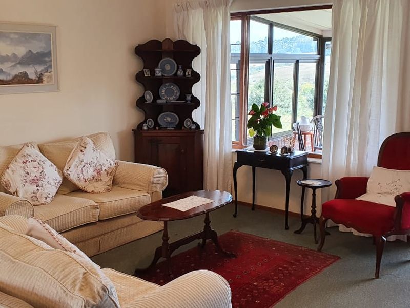 A comfortable living room featuring large windows and a sliding door that provides access to an outdoor patio area with scenic views.