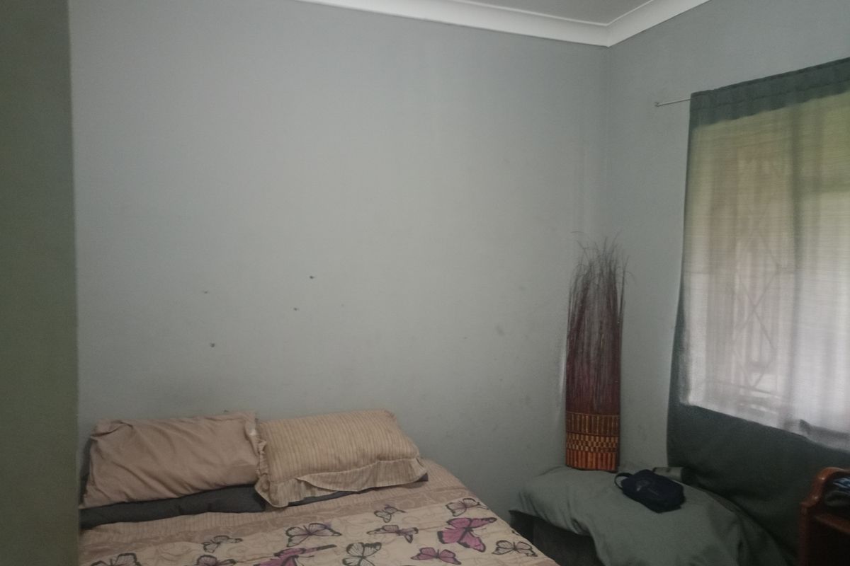 A standard bedroom featuring neutral wall paint, a window with curtain fixtures, and coved ceiling detailing.