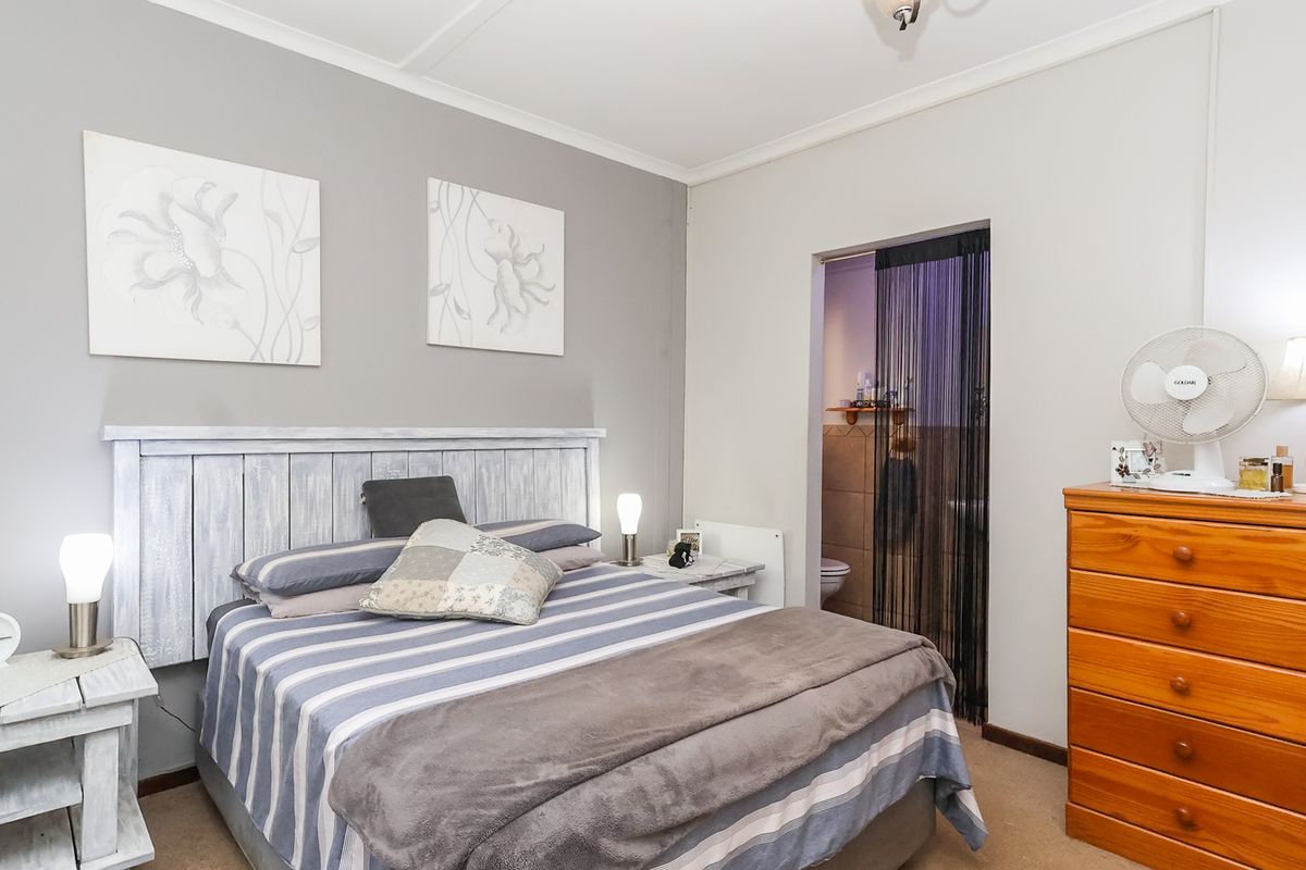 A well-maintained bedroom featuring neutral wall tones, coving, and direct access to an adjoining bathroom area.