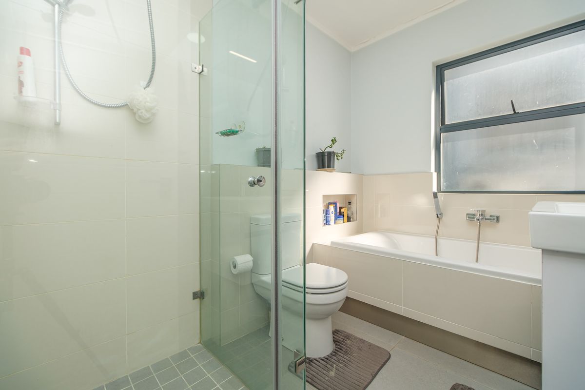 A clean, modern bathroom featuring a glass-enclosed shower, a built-in bathtub, and a recessed wall niche for storage.