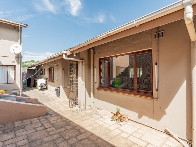 A paved rear exterior area featuring security gates, guttering, and downpipes, providing access to the side of the property.