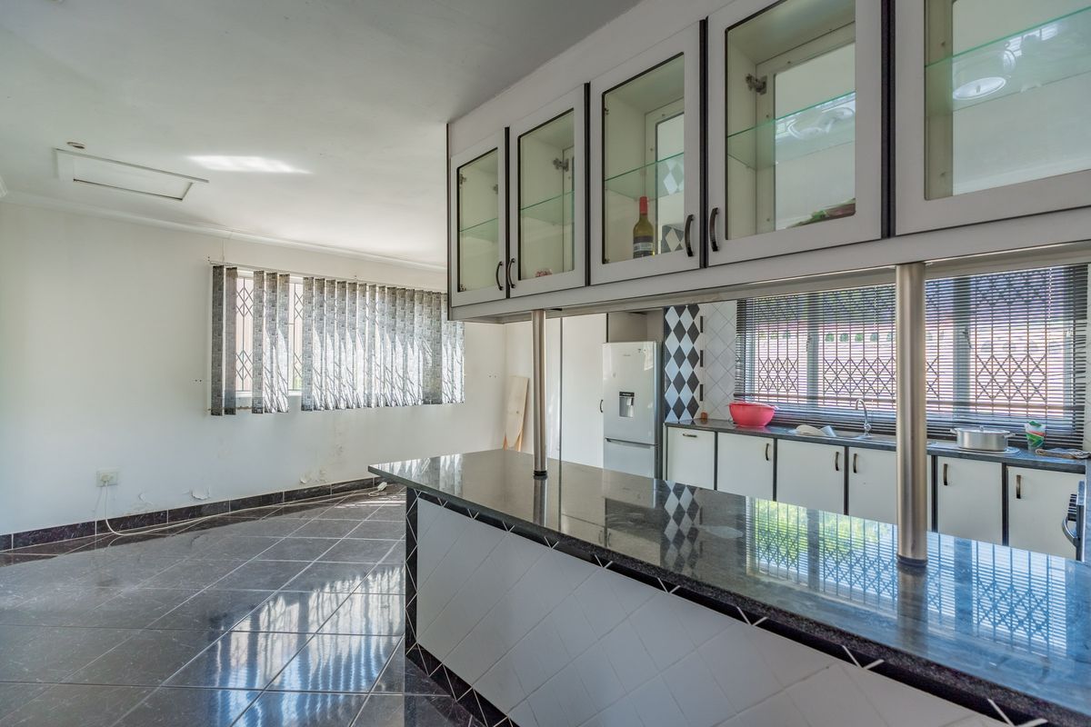 Spacious kitchen featuring granite countertops, a breakfast bar, and ample cabinetry, currently vacant and ready for a modern update.