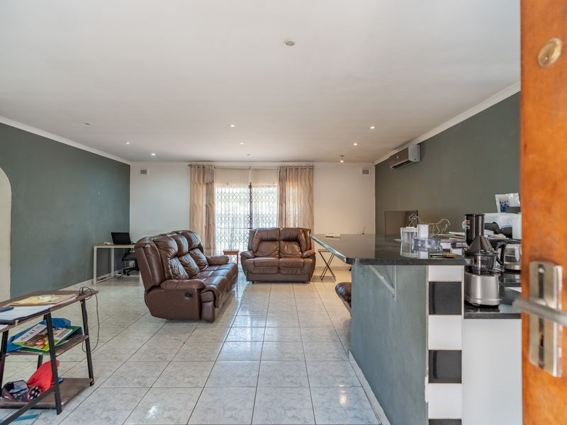 Spacious open-plan living area featuring tiled flooring, recessed lighting, and a granite kitchen breakfast bar, providing a versatile layout for dining and relaxation.