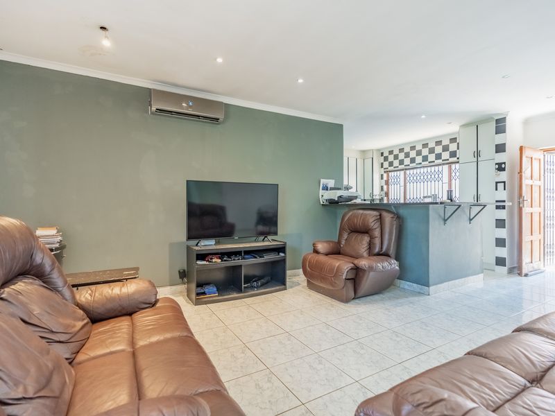Open plan living area featuring tiled flooring, recessed lighting, an air conditioning unit, and a breakfast bar connecting to the kitchen space.