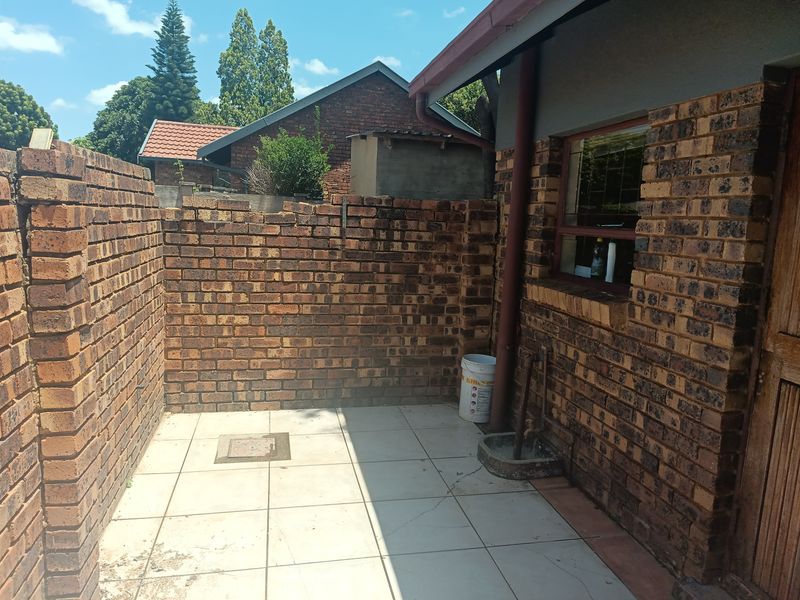 A small, paved rear courtyard area featuring brick boundary walls, an external tap, and tiled flooring, suitable for a private outdoor utility space.