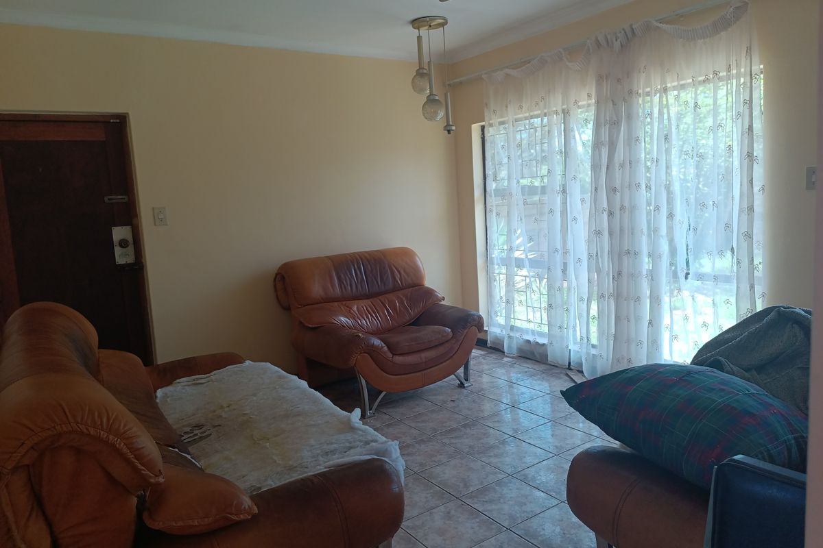 A living room featuring tiled flooring, a ceiling fan, and a sliding glass door with security gate leading to the exterior.