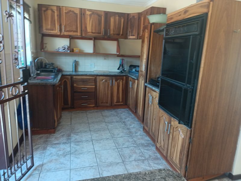 A dated kitchen featuring wooden cabinetry, built-in double oven, laminate countertops, and tiled flooring, offering potential for a modern renovation.