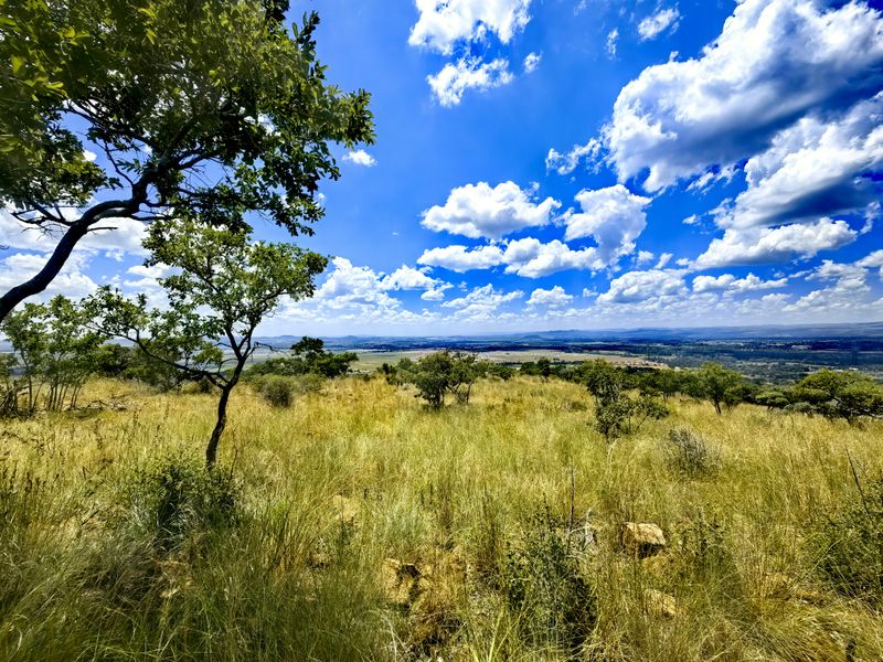 A scenic, elevated view overlooking expansive natural landscape and rolling hills, showcasing the property's open terrain and natural vegetation.