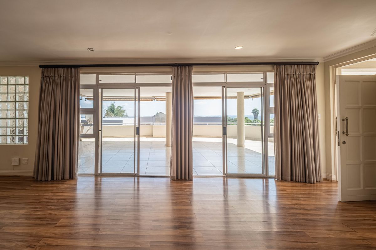 Spacious living area featuring laminate flooring, recessed lighting, and large sliding glass doors opening onto a covered balcony with exterior views.
