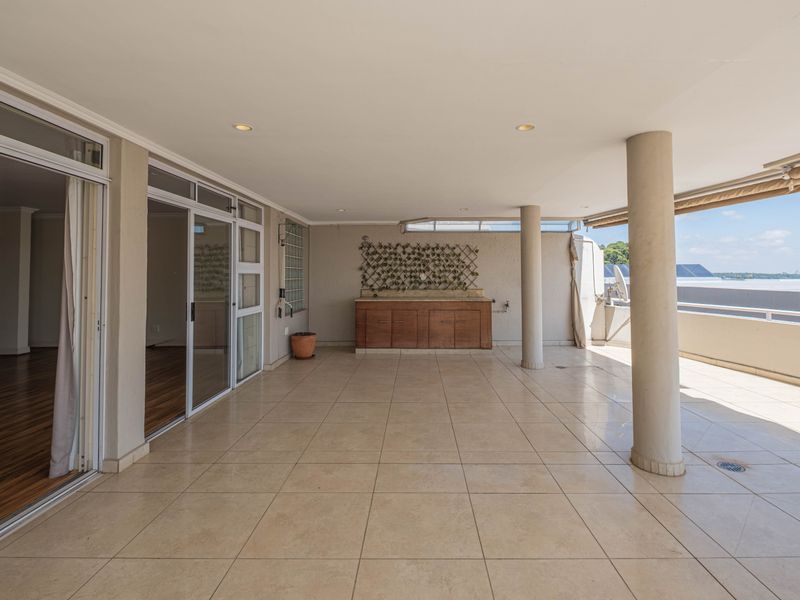 Spacious covered balcony featuring tiled flooring, built-in cabinetry, and sliding glass door access to the interior living area.