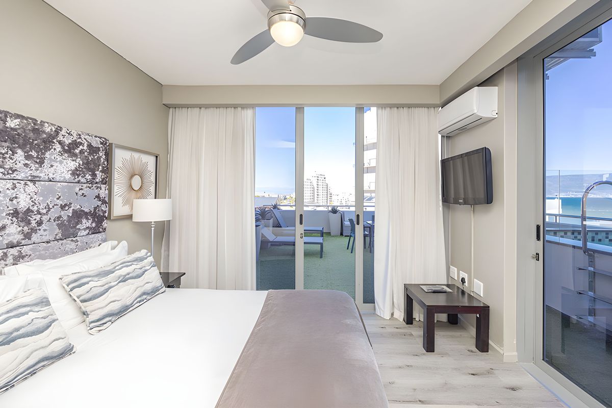 Modern bedroom featuring a ceiling fan, wall-mounted air conditioning unit, and large sliding glass doors providing direct access to a private balcony.