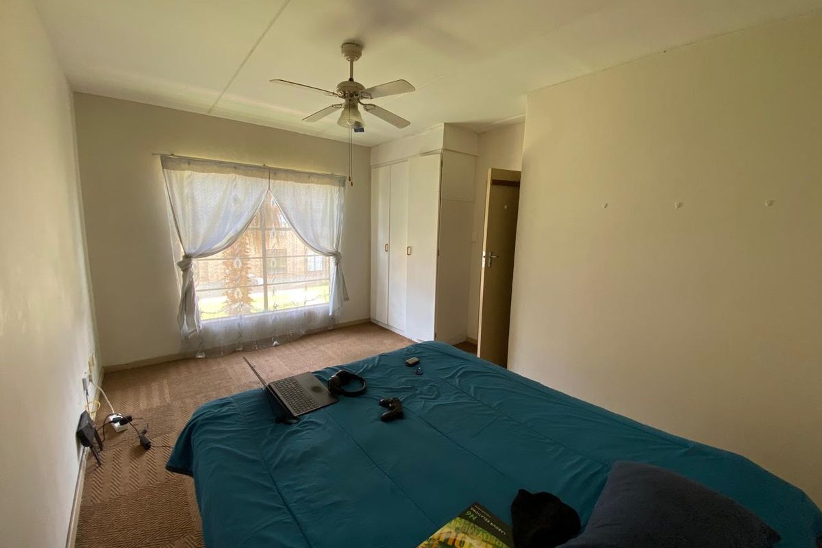 A functional bedroom featuring built-in cupboards, a ceiling fan, and carpeted flooring, offering a neutral canvas for potential updates.