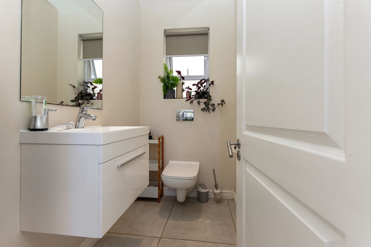 A modern, compact bathroom featuring a wall-mounted vanity with basin, wall-hung toilet with concealed cistern, and neutral tiled flooring.