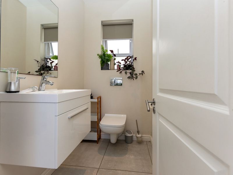 A modern, compact bathroom featuring a wall-mounted vanity with basin, wall-hung toilet with concealed cistern, and neutral tiled flooring.