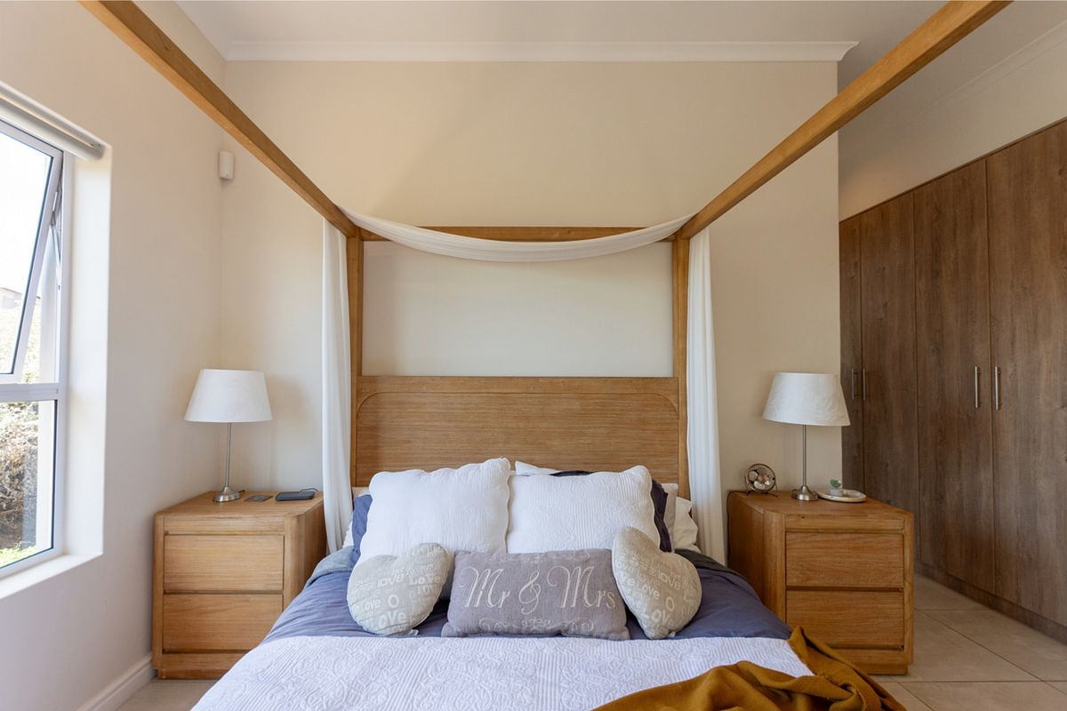 A well-maintained bedroom featuring built-in wooden cupboards, tiled flooring, and neutral wall finishes, providing a clean and functional living space.