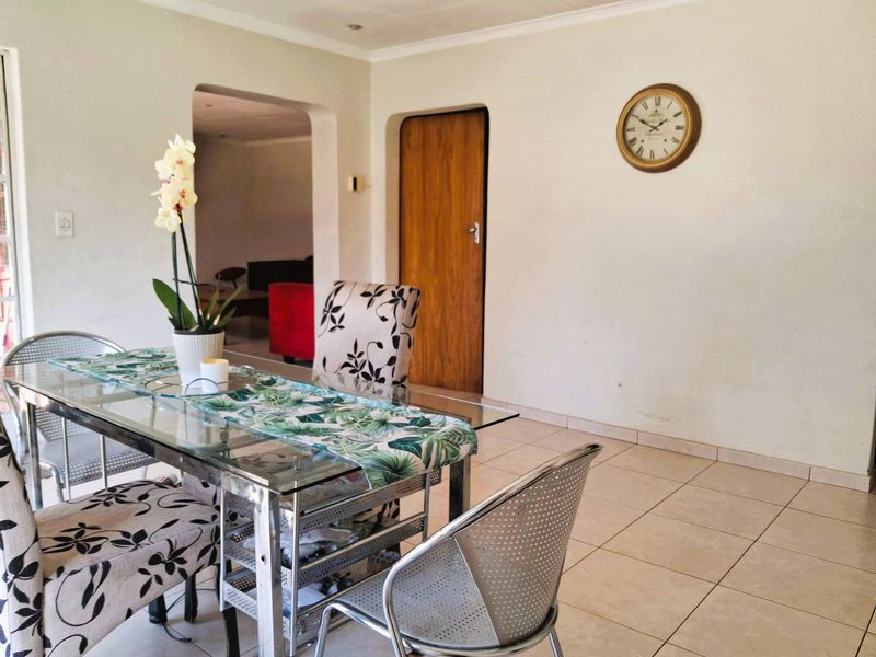 A dining area featuring tiled flooring and an arched doorway leading to an adjacent living space.