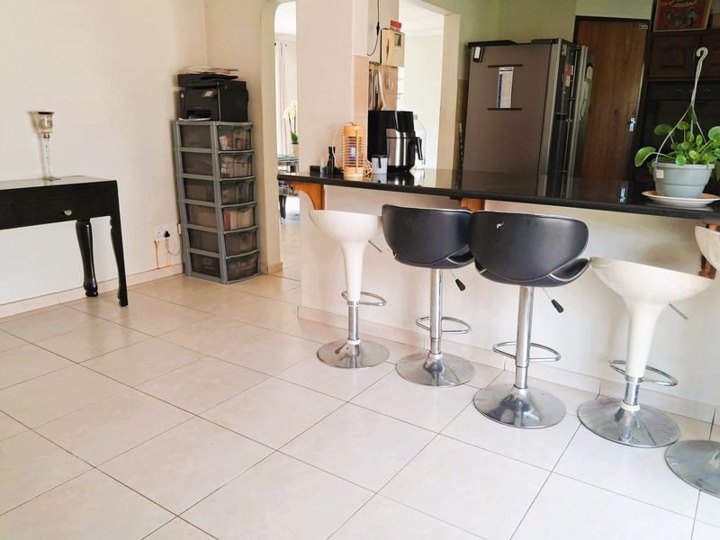 Open plan living and kitchen area featuring a breakfast bar with granite countertop and tiled flooring throughout.