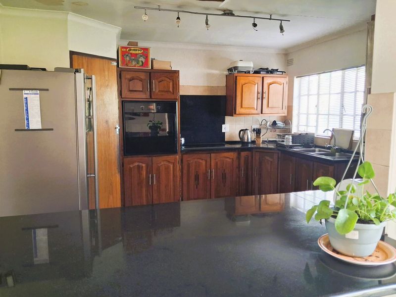 A functional kitchen featuring dark granite countertops, wooden cabinetry, a built-in oven, and a breakfast island, offering a classic layout with ample storage space.