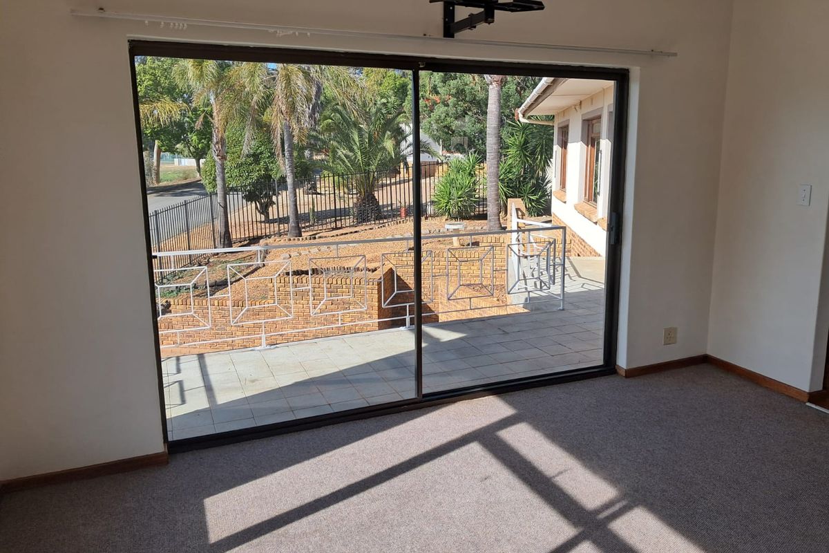 Interior view of a living space featuring large sliding glass doors that open onto a paved patio area with brick retaining walls.