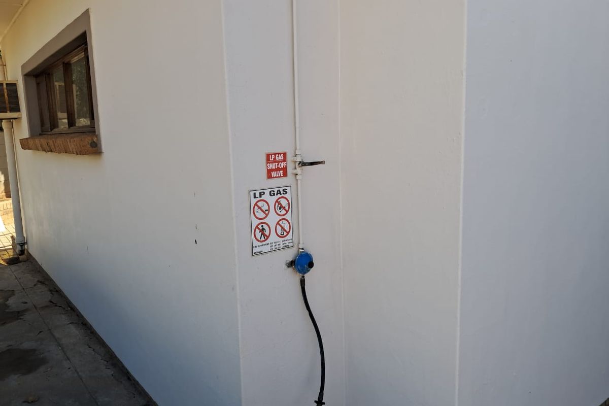 Exterior wall showing a fixed LP gas supply line with a shut-off valve and safety signage.