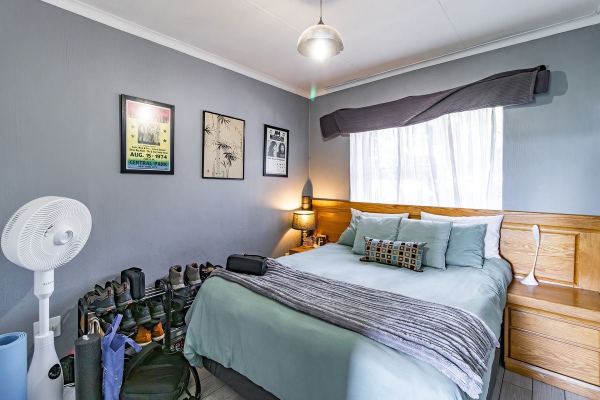 A cozy bedroom featuring a built-in wooden headboard with integrated bedside tables and neutral grey wall finishes.