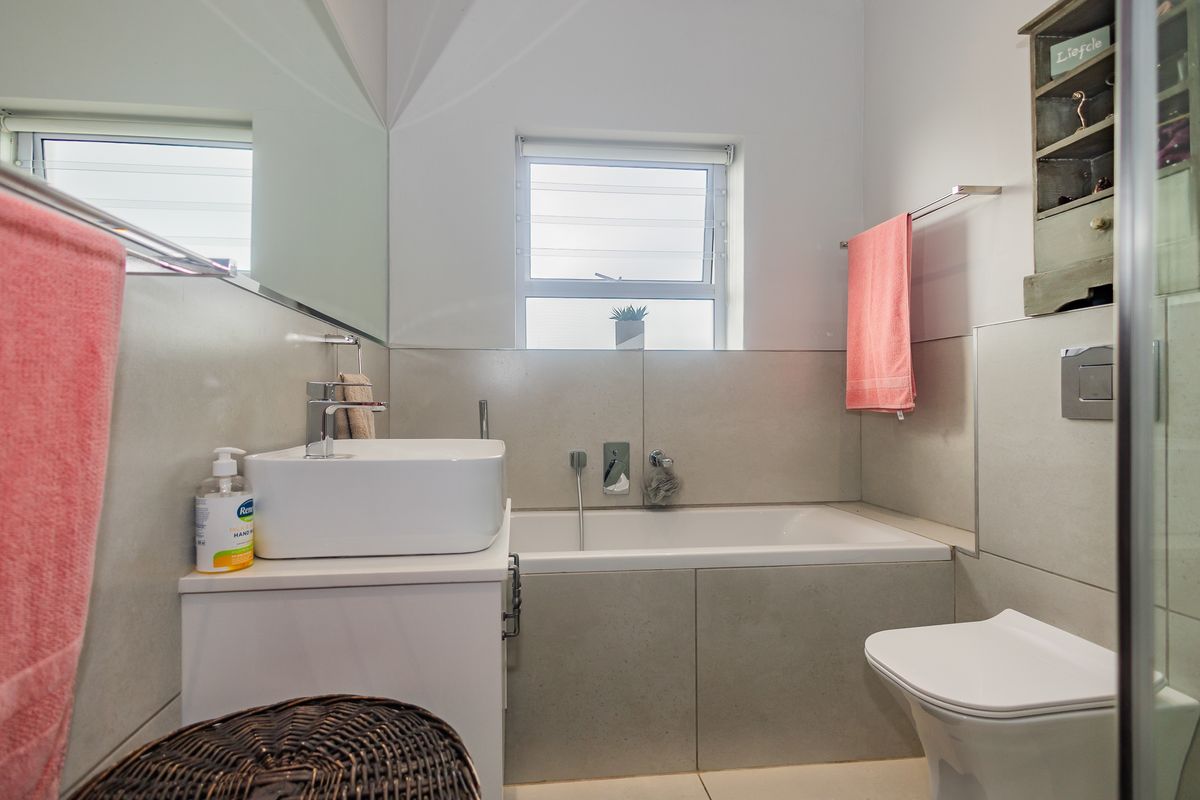 Modern bathroom featuring a vessel sink, wall-mounted faucet, built-in bathtub, and a wall-hung toilet with a concealed cistern.