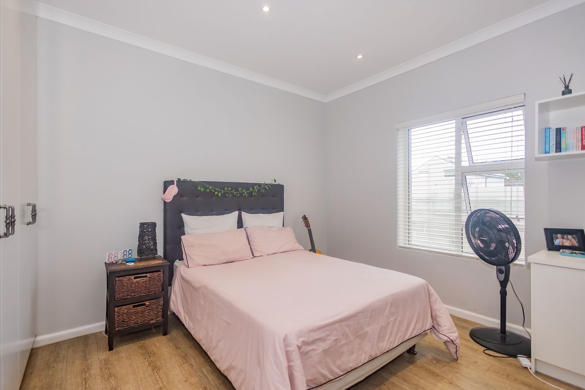 A well-maintained bedroom featuring laminate flooring, recessed downlights, built-in wardrobe, and built-in shelving, offering a clean and functional living space.