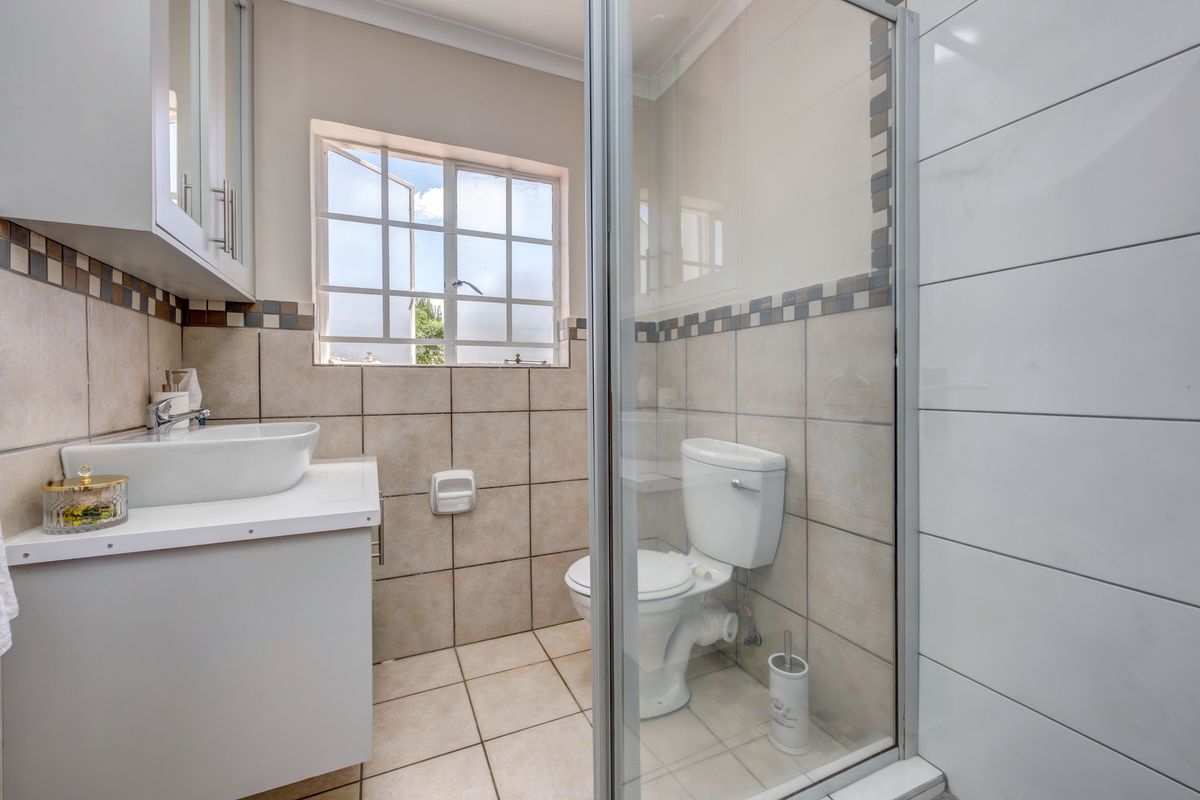 A functional bathroom featuring a shower enclosure, vanity cabinet with a vessel sink, and tiled finishes throughout.