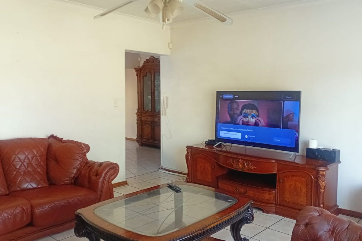 A living room featuring tiled flooring and a ceiling fan, providing a functional space with access to an adjacent room.
