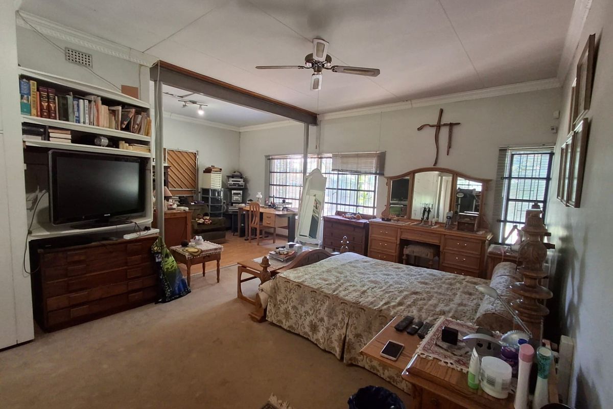 Spacious bedroom featuring a ceiling fan, built-in shelving, and a structural steel beam, offering potential for modernization and layout optimization.