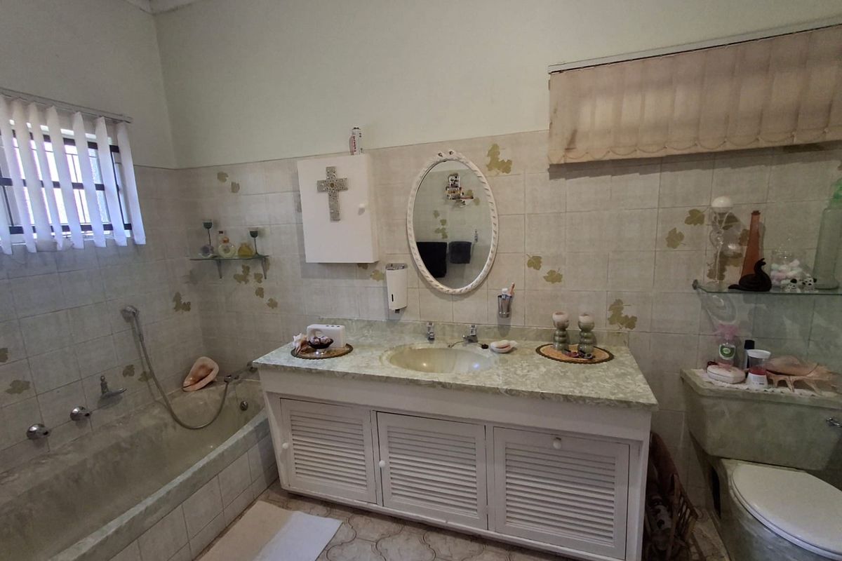A dated bathroom featuring a built-in vanity, bathtub, and toilet with original tiled finishes, offering significant potential for a modern renovation.