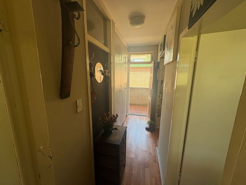 A functional hallway featuring built-in storage cupboards, laminate flooring, and direct access to an outdoor area.