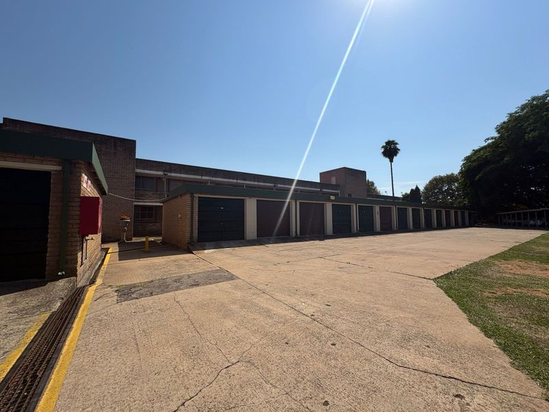 A row of multiple garage units with a concrete driveway and brick exterior finish.