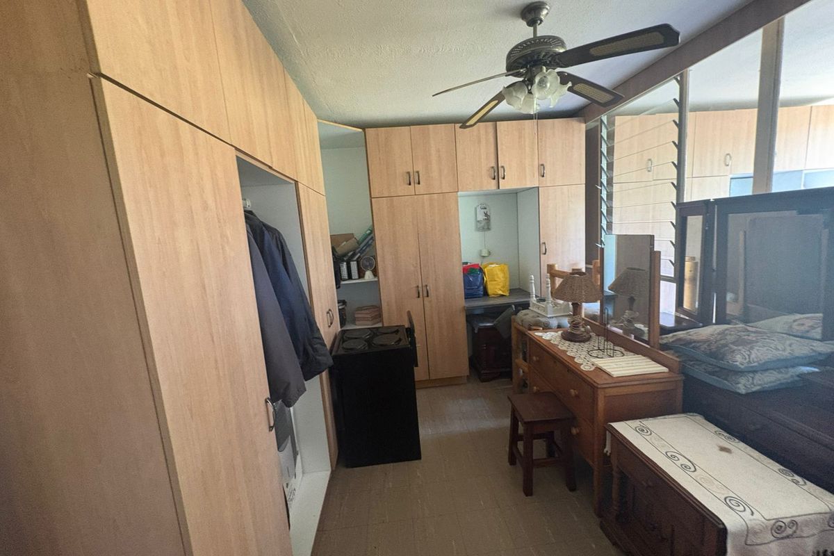 Bedroom featuring extensive built-in wooden cabinetry, mirrored wardrobe doors, and a ceiling fan, providing ample storage space.