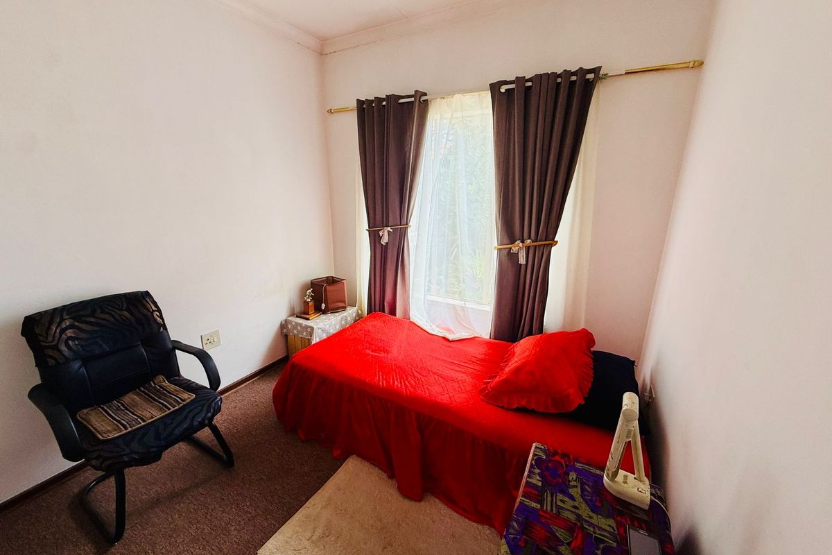 A compact bedroom featuring carpeted flooring and a window with curtain rod fixtures.