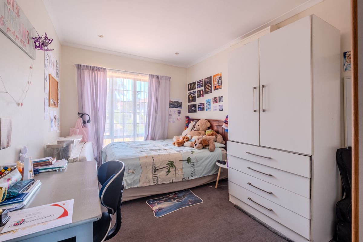 A functional bedroom featuring a built-in wardrobe, carpeted flooring, and recessed downlights, offering a comfortable space with natural light.