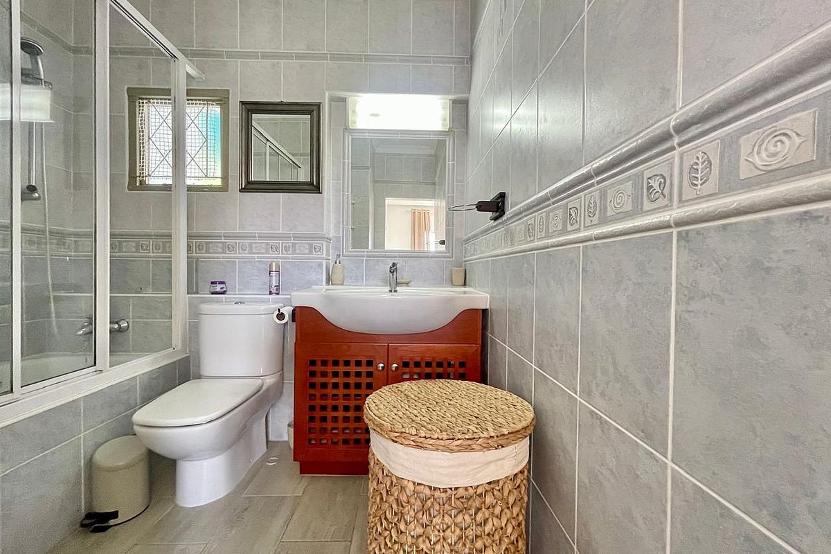 A functional bathroom featuring a shower enclosure, a vanity unit with a basin, and a toilet, finished with neutral wall and floor tiling.