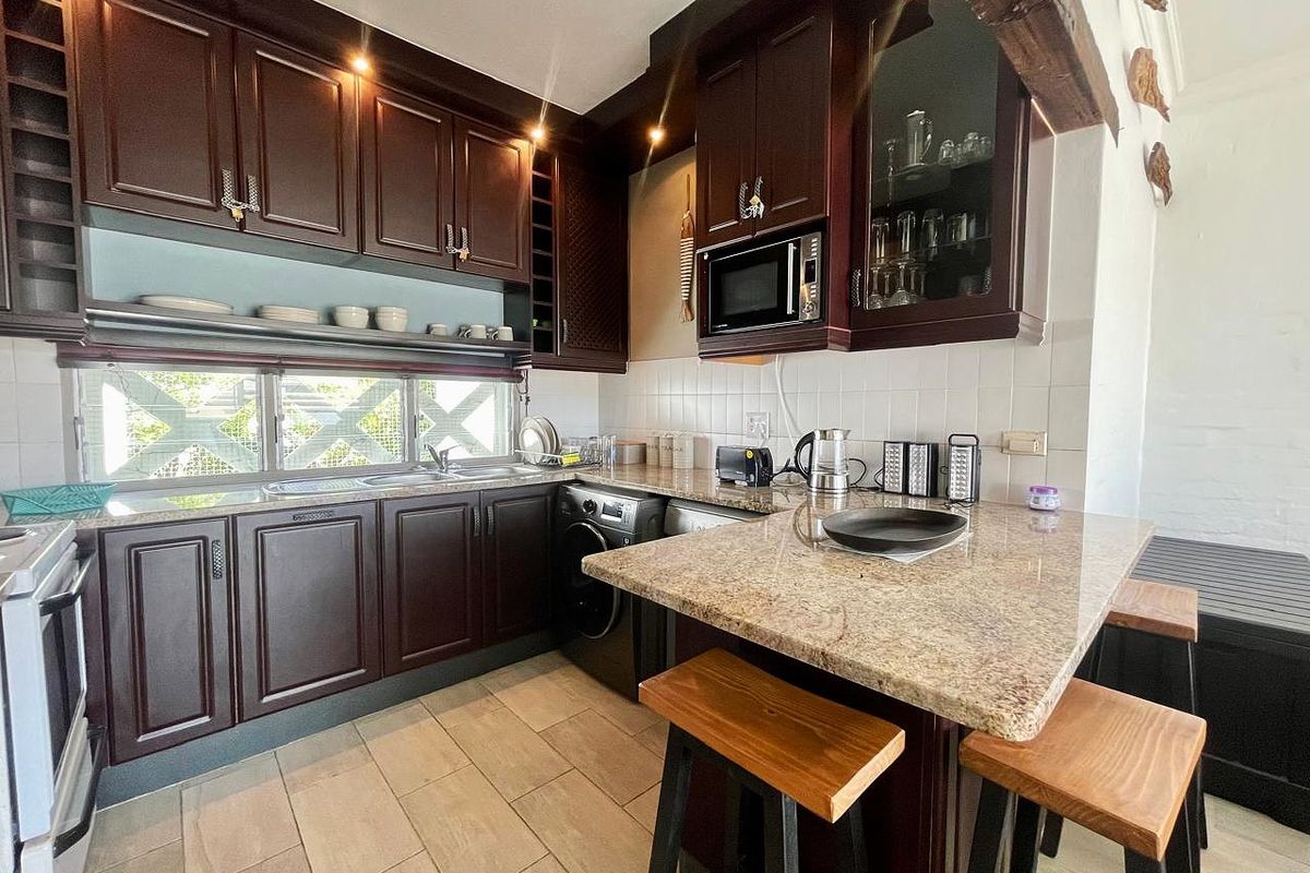 A functional kitchen featuring dark wood cabinetry, granite countertops, a breakfast bar, and integrated appliance space, offering a classic aesthetic with practical layout.