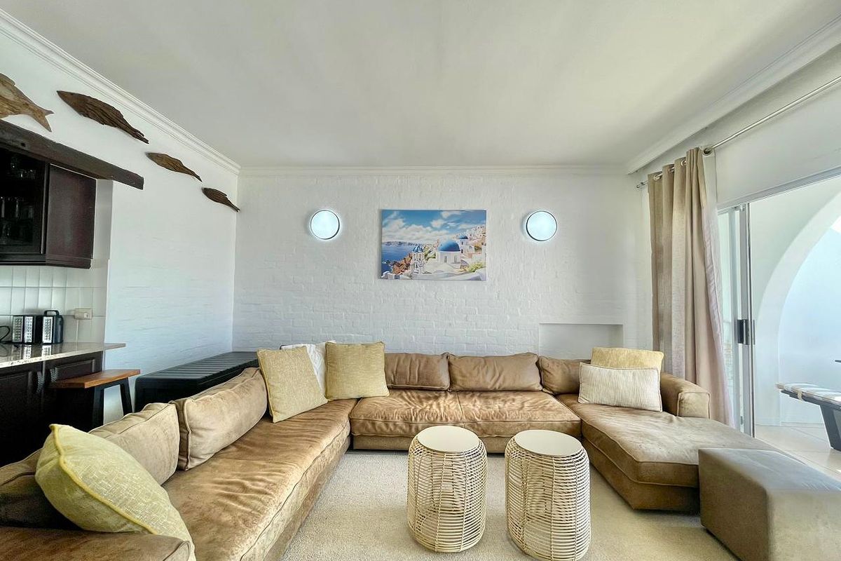 A comfortable living room featuring white painted brick walls, recessed lighting, and sliding glass doors leading to an outdoor patio area.