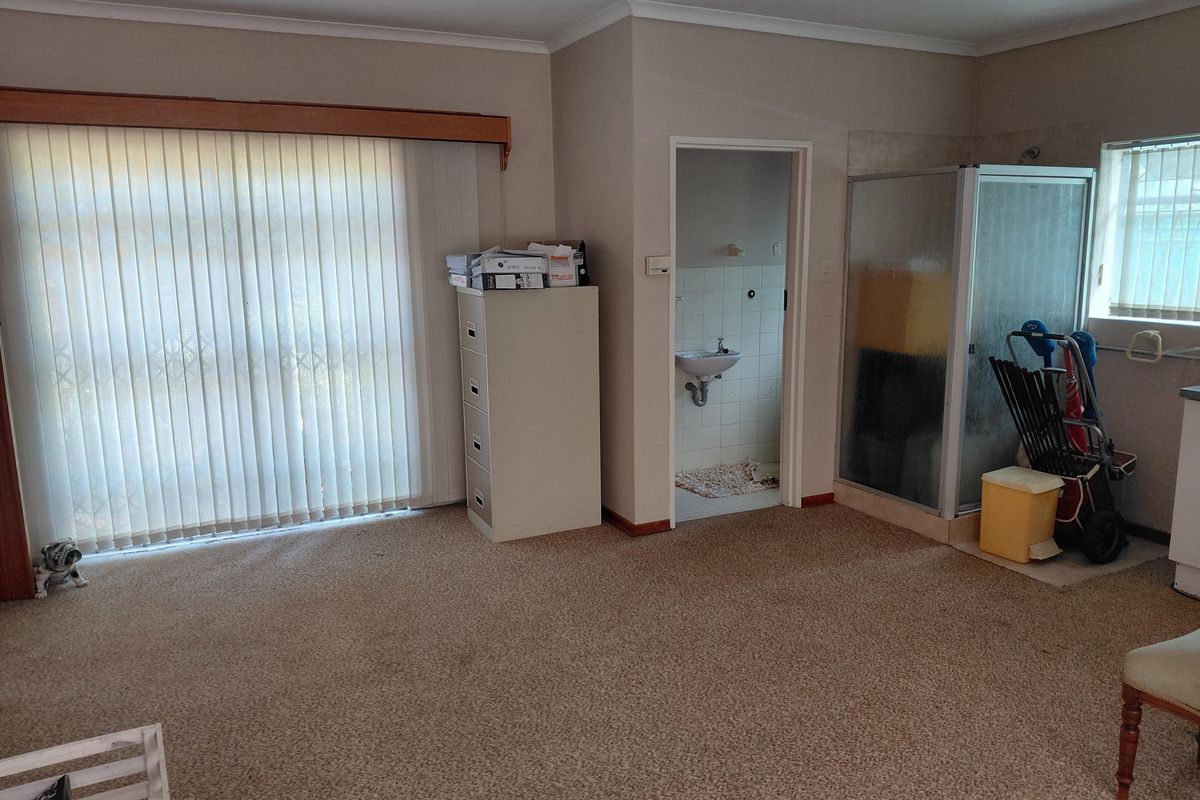 Spacious bedroom featuring an en-suite bathroom with a shower cubicle and wall-mounted basin, offering potential for modernization and layout optimization.